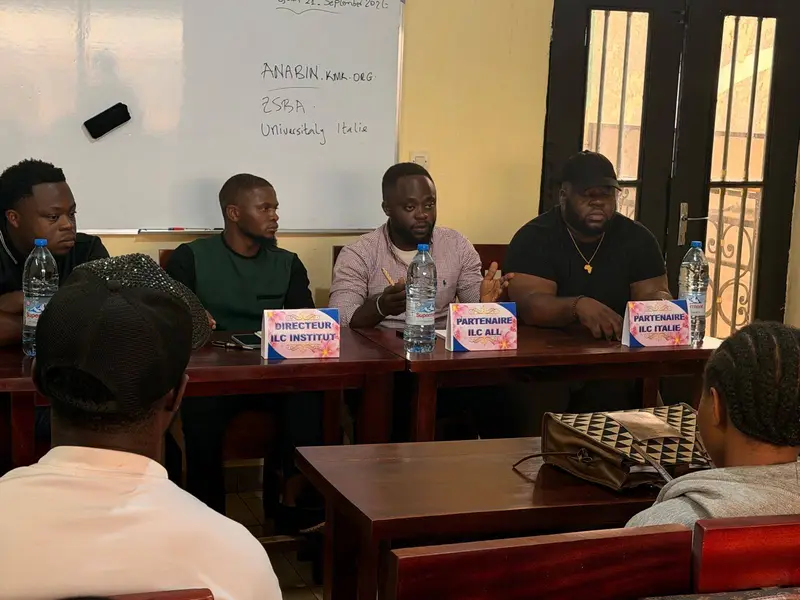 Une séance d’information chez ILC Institut : le directeur et des partenaires, assis derrière une table avec leurs chevalets, face au public.