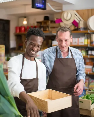 Deux vendeurs en tablier dans un magasin.