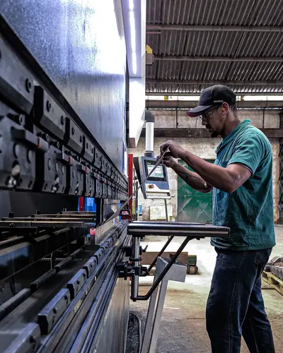 Un technicien règle une machine dans un atelier industriel.